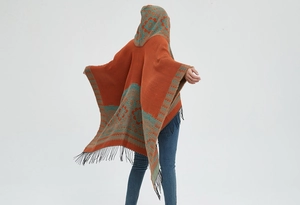 Détail de poncho à capuche bohème orange avec motifs jacquard et finitions à franges