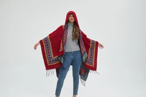 Détail d'un poncho rouge à capuche avec motifs ethniques de cœur et ourlet à franges noires