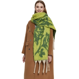 Winter chunky knit scarf with green floral jacquard and beige tassel accents on coat