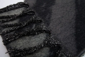 Close-up of thick grey and black plaid scarf featuring soft fringe and woven texture