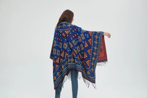 Detail view of ethnic geometric jacquard pattern and long black fringe on hooded poncho