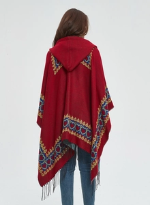 Détail du motif ethnique à cœur et des franges noires sur le poncho rouge à capuche