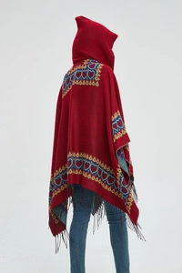 Détail d'un poncho rouge à capuche avec motifs cœurs bleus et franges noires