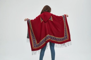 Gros plan du poncho rouge à capuche avec motifs jacquard cœur et détails de franges