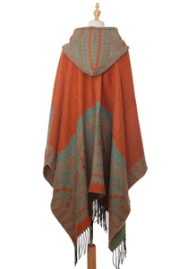 Détail du poncho à capuche rouge rouille avec motifs floraux vintage et bordures à franges