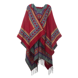 Détail d'un poncho ethnique rouge avec motifs de cœurs géométriques et franges noires