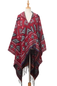 Detail of red hooded poncho with geometric jacquard patterns and long black tassels