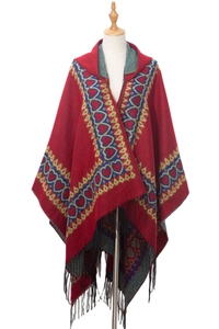 Détail d'un châle à capuche rouge avec motifs ethniques de cœur et finitions à franges