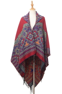 Gros plan sur un châle en tricot ethnique rouge à motif floral et franges à glands noirs