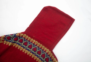 Détail du poncho à capuche rouge avec motifs de cœur bleus et broderies dorées