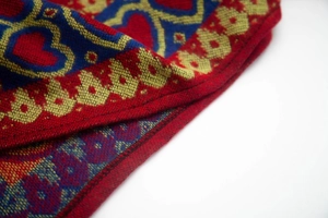 Détail du bord à franges rouges avec motif cœur sur le tissu de poncho ethnique