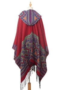 Gros plan du poncho à capuche rouge avec motifs bohèmes et longues franges noires