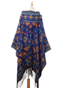 Detail of blue hooded knit poncho featuring geometric tribal patterns and black fringe