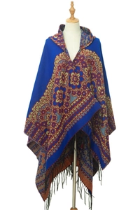 Détail d'un poncho à capuche bleu aux motifs ethniques floraux et franges noires