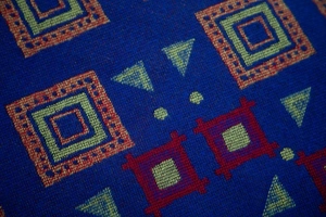 Macro shot of blue woven fabric with red and yellow geometric jacquard patterns