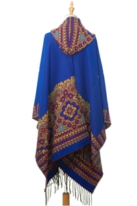 Détail d'un poncho bleu à capuche avec jacquard ethnique et bordure à franges noires