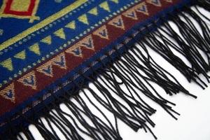 Close-up of geometric pattern jacquard weave and black fringe detail on hooded poncho cape