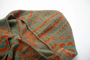 Détail du tissu jacquard orange et cyan avec motifs floraux ethniques et vagues tissées