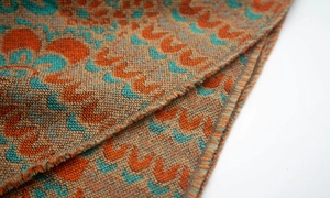 Détail d'un poncho en maille bohème avec motifs géométriques et finitions à franges