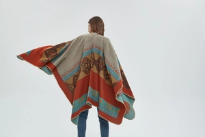 Close-up of Bohemian thick knit poncho with ethnic jacquard pattern and stitched edges