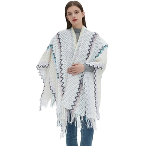 Women's white knitted poncho with ethnic geometric patterns and stylish fringe trim
