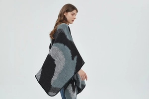 Close-up of thick knitted leopard pattern shawl with black overlocked edge detail