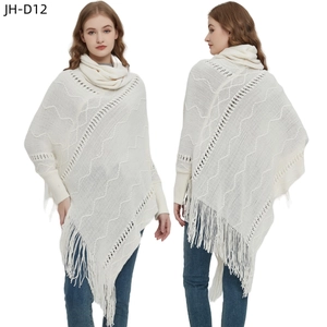 Nahaufnahme von weißem Strickponcho mit Fransen, Wellenstruktur und passendem Halskragen