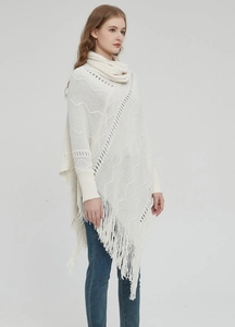 Nahaufnahme von weißem Strickponcho mit Stehkragen und langen Fransen am Saum
