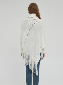 Nahaufnahme eines beigen Strickponchos mit Rollkragen, Fransen und geometrischer Textur
