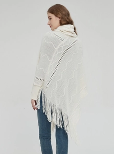 Detail eines weißen Strickschals mit Rollkragen, Zopfmustern und langen Fransen