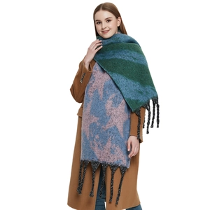 Thick knitted scarf with blue-green star pattern and tassels on brown wool coat