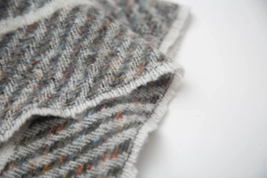 Detailed macro shot of grey herringbone knit scarf with colorful fiber accents