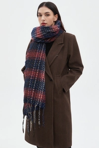Vista dettagliata della sciarpa a quadri rossa, blu e beige con nappe su cappotto