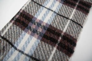 Close-up of thick plaid scarf featuring blue and grey brushed fabric with soft fringe details