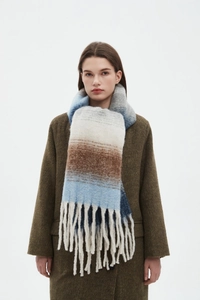 Close-up of thick knitted scarf with gradient stripes and long fluffy tassels on a model