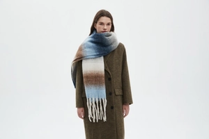 Detail of thick winter scarf with blue and beige gradient stripes and long fringes