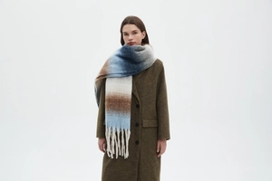 Detail of soft gradient chunky knit scarf with long tassels and thick winter texture