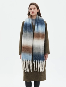 Close-up of thick tassels and gradient knit texture on a winter blanket scarf