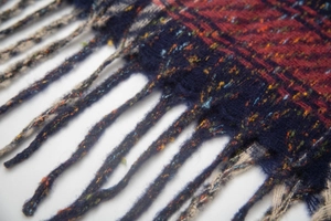 Dettaglio macro di sciarpa a quadri con fibre colorate e finiture con frange a torsione