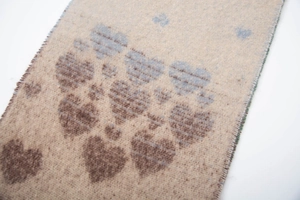Macro view of beige knit scarf showing heart patterns and soft faux mohair texture