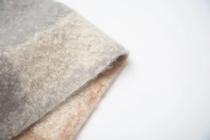 Vista dettagliata della sciarpa a quadri con trama in tessuto bouclé grigio e beige