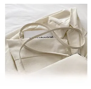 Detail of adjustable strap and silver butterfly buckle on cream white shoulder bag