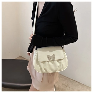 Detail view of the beige pleated shoulder bag with a silver butterfly metal buckle