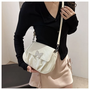 Detail of white pleated shoulder bag with silver butterfly buckle on adjustable strap