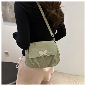 Detail of mint green pleated crossbody bag featuring a silver butterfly clasp and soft texture