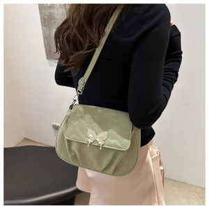 Detail of light green pleated shoulder bag with silver butterfly buckle and adjustable strap