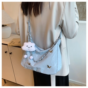 Detail of light blue pleated tote bag with silver chain and white cloud plush charm