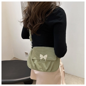 Detail of light green pleated shoulder bag with a silver butterfly metal clasp buckle