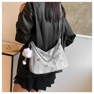 Detail of silver pleated shoulder bag with metal butterfly charm and chain strap
