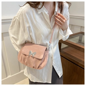 Close-up of pink pleated crossbody bag with a silver butterfly ornament and metal finish